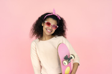 Happy smiling young african american teen girl black woman skater wear glasses hold skateboard...