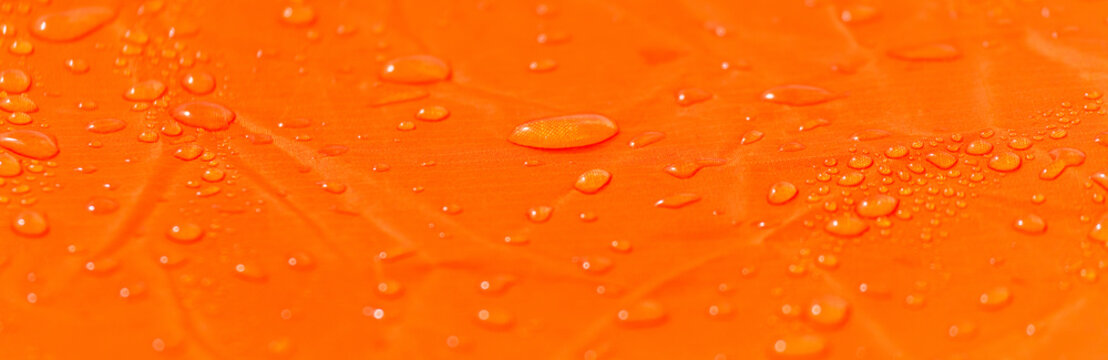 Raindrops on a tent of orange color as an abstract background
