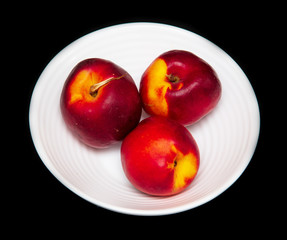 Ripe nectarine in a white plate on a black background