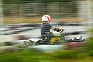 A young man on a go-kart rides at a frantic speed.