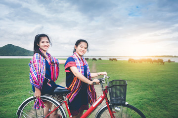 Beautiful Asian girls enjoy travel at countryside of Thailand by riding on bicycle