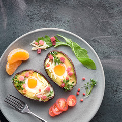 Keto diet dish: Avocado boats with ham cubes, quail eggs, cheese on dark with copy-space