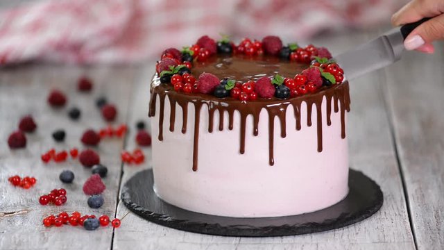 Beautiful homemade cake with summer berries, chocolate frosting on white table.