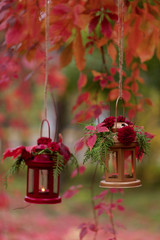 Fototapeta premium Fall time. Autumn decoration. Candlesticks in the form of lanterns with daisy decor, juniper and autumn red leaves.