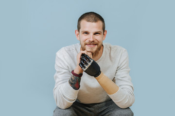 Young Man With Artificial hand is looking forward and smiling at the camera