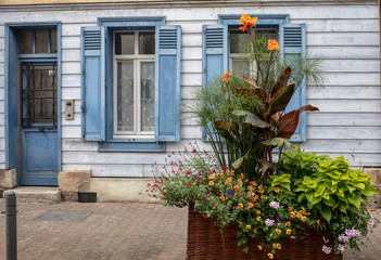 A beautiful, colorful flower bed in front of the blue facade of the Troyes house. Aube, Champagne-Ardenne, France