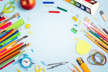 Back to school concept with school supplies and copy space on blue background.