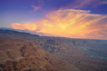 Fototapeta na wymiar Mountain nature landscape. View of the valley from the mountain. The Judean Desert in the early morning. Beautiful cloud over the mountains. Beautiful sunrise over Masada fortress. Israel.