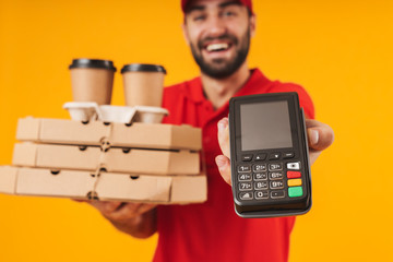 Portrait of caucasian delivery man in red uniform holding pizza boxes and payment terminal
