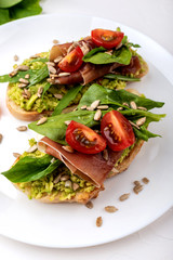 Sandwiches with avocado cream, tomatoes and jamon.