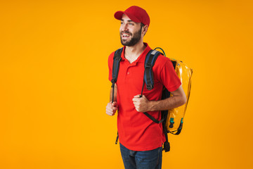 Photo of positive delivery man in red uniform carrying backpack with takeaway food