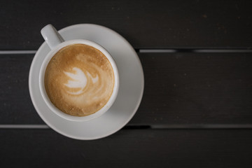 Cup of coffee with milk on dark wooden table