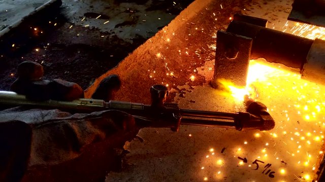 Male professional metalworker holding the oxy-acetylene torch and cutting steel  at the workshop in 4K