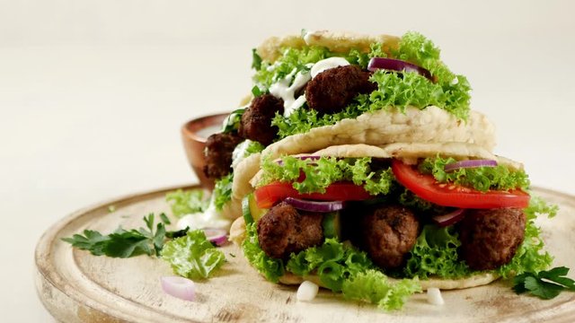 Kebab, kofta in pita, bun. Traditional southern European dish. Front view.  Turning the platter. Slow motion.