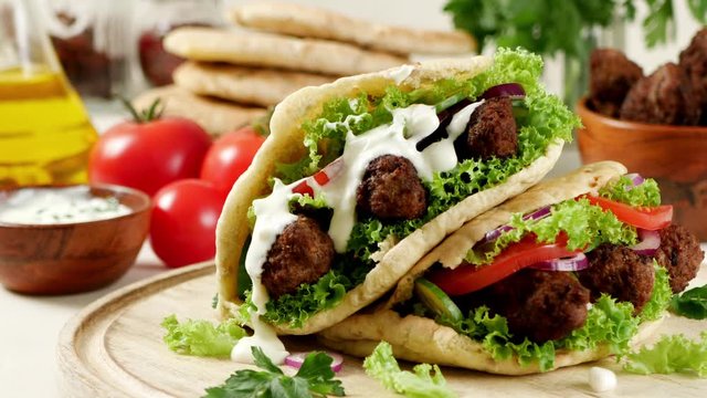 Kebab, kofta in pita, bun. Traditional southern European dish. Front view.  Turning the platter.