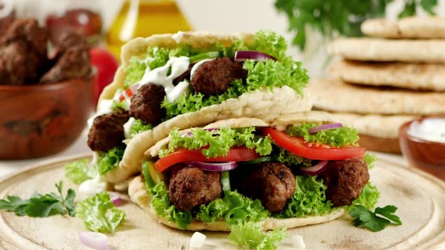 Kebab, kofta in pita, bun. Traditional southern European dish. Front view.  Food presentation. Turning the platter.