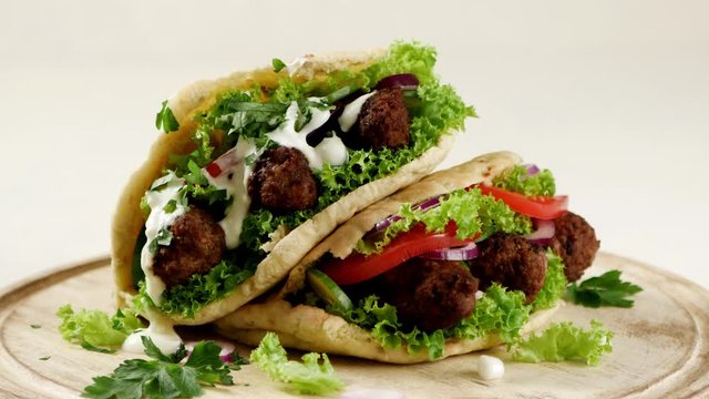 Kebab, kofta in pita, bun. Traditional southern European dish. Front view.  Food presentation. Turning the platter.