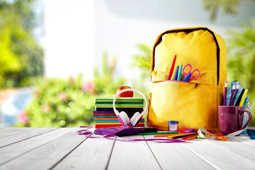 Table background and a schoolbag with some colorful school supplies. Empty space for advertising products and decoration. - obrazy, fototapety, plakaty