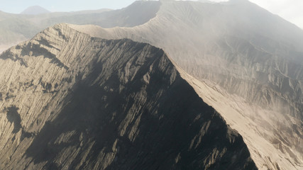Cinematic drone shot aerial view of Mount Bromo crater edge with active volcano smoke in East Java, Indonesia