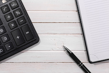 workplace with calculator, notepad and pen on the wooden table desk