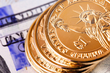 Fototapeta na wymiar closeup macro one dollar golden coins and hundred dollars banknotes