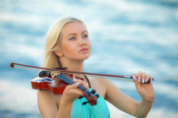 Girl on the beach plays the violin.