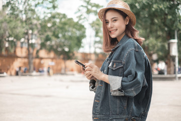 Smiling woman traveler in thapae gate landmark chiang mai thailand with backpack holding smartphone on holiday, relaxation concept, travel concept