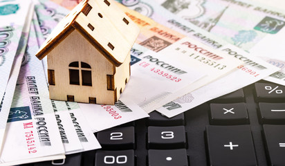finance concept in mini-house symbol and calculator with Russian money, rubles banknotes background