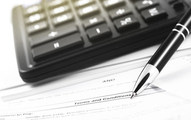 finance concept in paperwork, black calculator and pen closeup