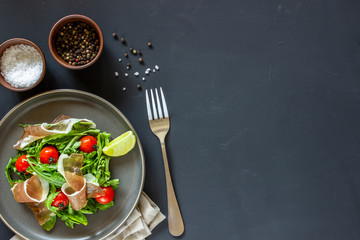 Salad with arugula, tomatoes and prosciutto. Italian cuisine. Healthy eating. Diet.