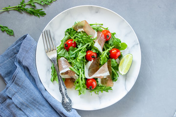 Salad with arugula, tomatoes and prosciutto. Italian cuisine. Healthy eating. Diet.