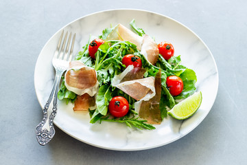 Salad with arugula, tomatoes and prosciutto. Italian cuisine. Healthy eating. Diet.