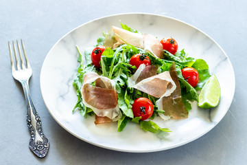 Salad with arugula, tomatoes and prosciutto. Italian cuisine. Healthy eating. Diet.