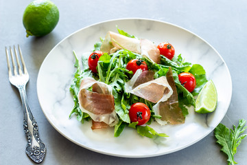 Salad with arugula, tomatoes and prosciutto. Italian cuisine. Healthy eating. Diet.