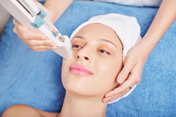 Pretty young smiling Caucasian woman having mesotherapy injection procedure in beauty salon