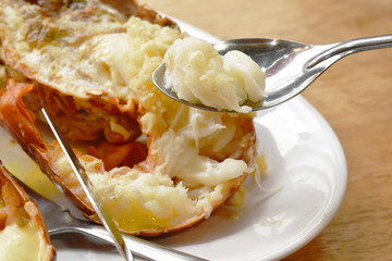 grilled lobster shrimp with cheese and butter garlic scooping by silver spoon on plate