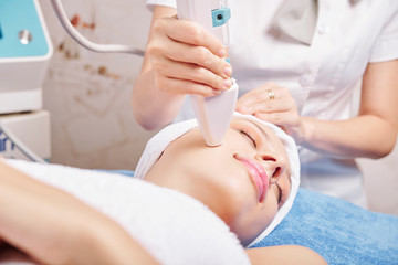 Obraz na płótnie Canvas Smiling Caucasian young woman enjoying anti-aging procedure in beauty salon