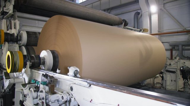 mechanism reels packaging paper on huge roll at plant