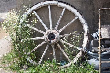 Big old wooden wheel leaning on concrete wall