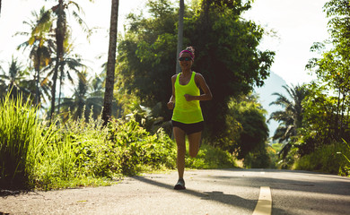 Young fitness woman running at tropical forest trail