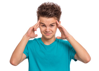 Fototapeta premium Portrait of teen boy touching his head suffering headache looking tired and sad. Unhappy beautiful caucasian young teenager suffering from headache, isolated on white background.