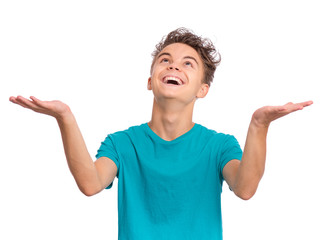 Portrait of teen boy raised hands and trying to catch something. Cute caucasian young teenager smiling and looking up, isolated on white background. Joyful child having fun.