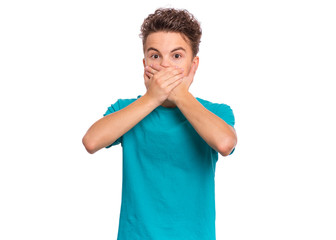 Portrait of amazed teen boy covers his mouth with hands. Child with very large eyes in surprise looking at camera. Caucasian young teenager, isolated on white background. Speak no evil concept. - 283493581