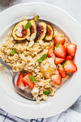 Quinoa breakfast porridge with strawberries and figs in white plate. Healthy breakfast concept.
