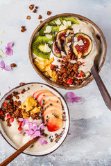 Smoothie bowl with fruit and granola with coconut shell bowl on gray background. Healthy vegan food concept.