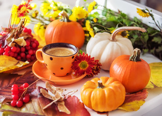A cup with a steaming drink and autumn red berries of viburnum. Autumn cozy home still life.