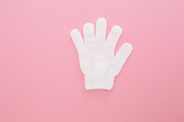 Obraz premium Woman exfoliating massage glove for shower on pink background.Gloves for use in the shower for massage and scrub. Beauty background with cosmetic products. Beauty, health and spa concept