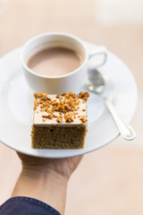 Man hand holding a cup of coffee and cake.