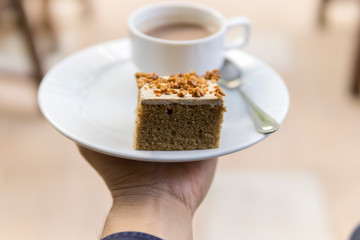 Man hand holding a cup of coffee and cake.