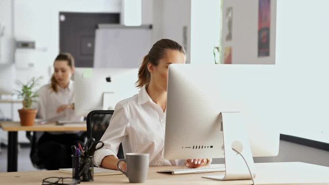 Young beautiful concentrated woman working in office using pc computer writing notes